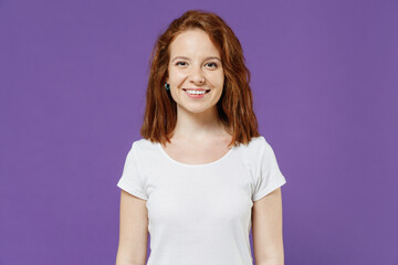 Fototapeta premium Young smiling happy cheerful friendly caucasian woman 20s wearing white basic blank print design t-shirt looking camera isolated on dark violet background studio portrait. People lifestyle concept