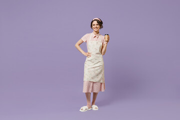 Full length fun young housewife housekeeper chef baker woman in pink apron t-shirt hold takeaway delivery craft paper brown cup coffee to go isolated on pastel violet background. Cooking food concept