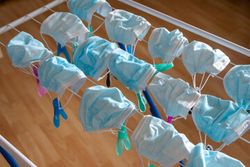 Washed surgical masks hanging on a clothes drying rack after disinfection as hygienic new normal in...