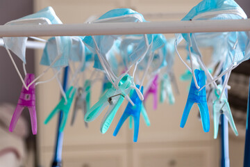 Washed surgical masks hanging on a clothes drying rack after disinfection with clothespins in...