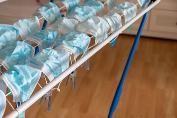 Washed surgical masks hanging on a clothes drying rack after disinfection as hygienic new normal in...