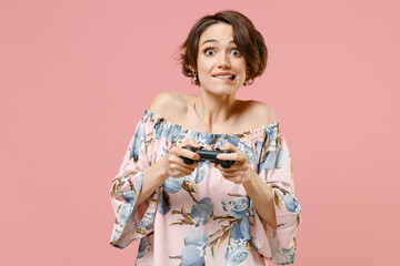Obraz na płótnie Canvas Young excited happy gambling fun caucasian woman 20s with short hairdo wearing trendy stylish blouse playing pc game with joystick console isolated on pastel pink color background studio portrait