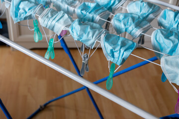 Washed surgical masks hanging on a clothes drying rack after disinfection with clothespins in pandemic times with covid-19 in quarantine to medical protection with face masks as essential item