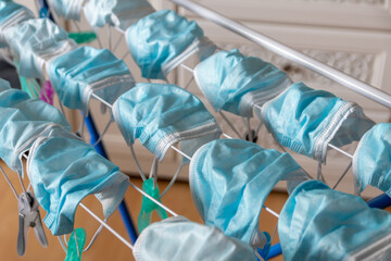 Washed surgical masks hanging on a clothes drying rack after disinfection as hygienic new normal in pandemic times with covid-19 in quarantine to medical protection with face masks as essential item