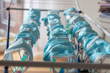 Washed surgical masks hanging on a clothes drying rack after disinfection as hygienic new normal in...