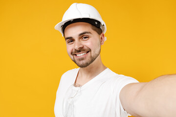 Close up young employee handyman man in protective helmet hardhat doing selfie shot on mobile phone isolated on yellow background Instruments accessories renovation apartment room Repair home concept