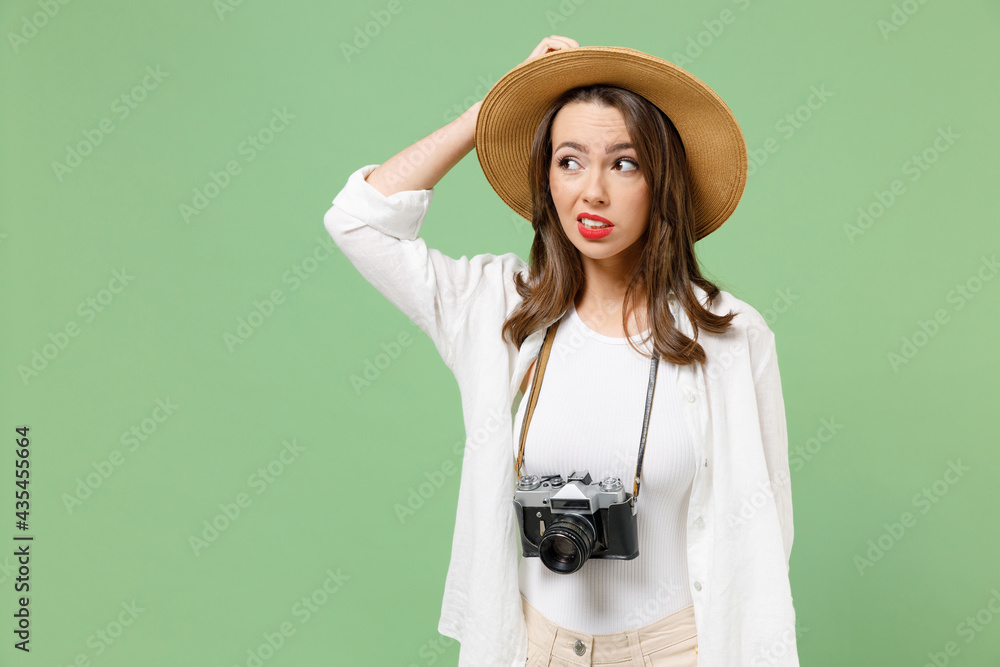 Wall mural traveler puzzled pensive tourist woman in casual clothes hat camera on neck look aside scratch head 