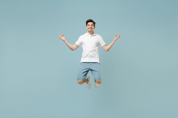 Obraz premium Full size young caucasian man 20s in white casual basic t-shirt hold spread hand in yoga om aum gesture relax meditate try to calm down jump high levitating isolated on pastel blue background studio