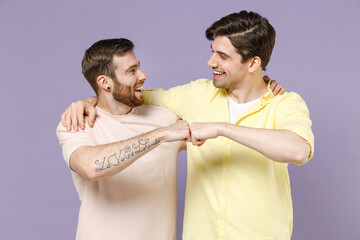 Two young happy positive cool men friends together in casual tshirt tattoo translate fun give fist...