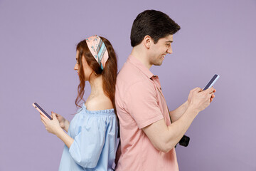 Two side view fun traveler tourist woman man couple in shirt use mobile cell phone stand back to...