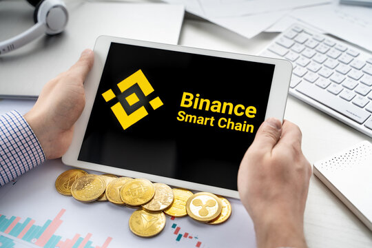 Businessman holding tablet with logo of cryptocurrency decentralized exchange protocol Binance Smart Chain. Trading blockchain platform to buy, sell, change crypto coins, tokens, diital money