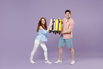 Fototapeta na wymiar Full length two fun traveler tourist woman man couple in shirt holding suitcase fooling around isolated on purple background. Passenger travel abroad on weekends getaway. Air flight journey concept.