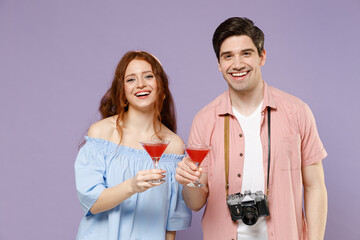 Two happy smiling cool traveler tourist woman man couple in summer shirt hold martini red alcohol cocktail isolated on purple background Passenger travel abroad weekends getaway Air flight concept