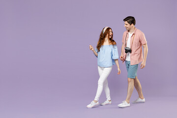 Full length side view two excited traveler tourist woman man 20s couple in summer clothes wlak go isolated on purple background Passenger travel abroad on weekends getaway. Air flight journey concept