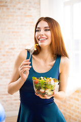 Portrait of happy amazed, smiling woman eating greece salad with cheese, indoor. Attractive girl in...