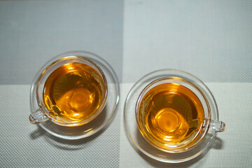 Top flat lay of two cups of tea kept in glass cup and saucer with copy space on top
