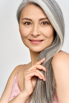 Vertical portrait of gorgeous happy joyful middle aged mature cheerful asian woman, senior older 50s gray haired lady isolated on white. Ads of hair care products for older salon haircare.