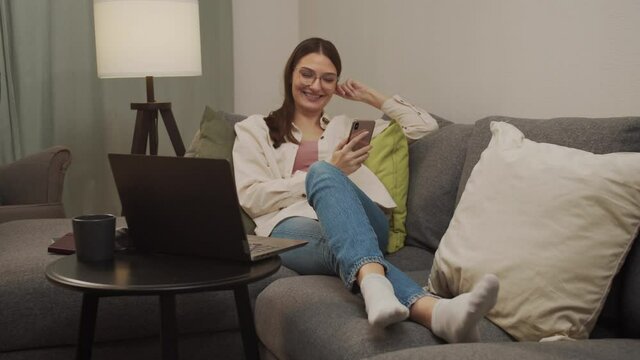 Beautiful woman lying on the couch, resting and talking on the phone.
