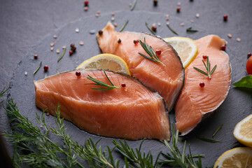 Fresh fish. piece of raw salmon fish fillet, spices on a black stone surface, Delicious fish meat. top view. Healthy food.