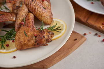 Roasted chicken wings in barbecue sauce and mixed vegetable salad with pepper seeds rosemary, salt in white plate on light color stone table. top view with copy space. tasty snack. Flat lay.