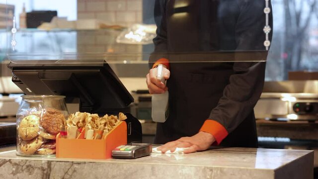 Cashier till till with antibacterial spray detergent Spbi. Cafe worker in uniform disinfect cash