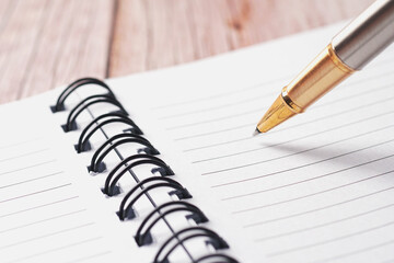 Golden pen and white paper notebook with lines