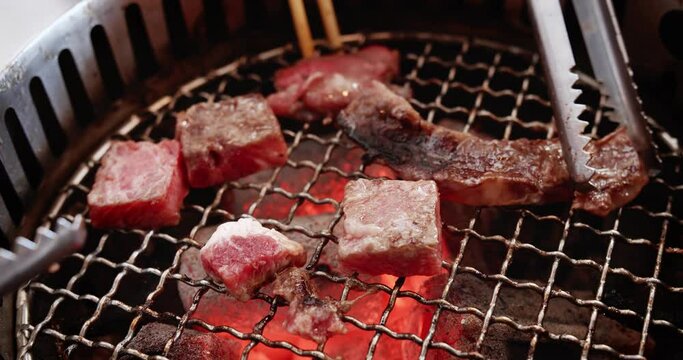 Close up roasting juicy raw meat beef slices bbq steak on charcoal grill with fire flame smoke, japanese style yakiniku bbq barbecue grill at restaurant