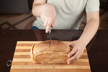 Young woman cutting bread with knife.