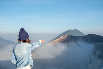 Cute girl Pointed his finger forward, where mist covered the mountain peak.