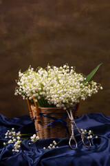 Still life with a bouquet of lilies of the valley in a basket