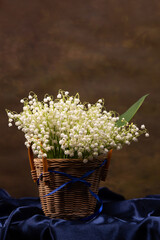 Still life with a bouquet of lilies of the valley in a basket
