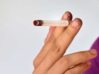 A burning cigarette between two fingers.