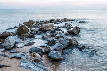Sea stones boulders sandy shore. Natural landscape.
