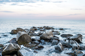 Sea stones boulders sandy shore. Natural landscape.
