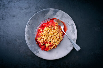 Modern style traditional American crumble cake with rhubarb and apple with backed topping served as top view on a design plate with copy space