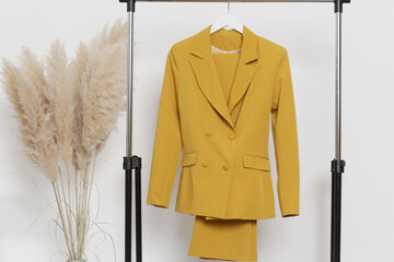 Women's Clothes. Clothes rack, yellow blazer and trousers in fashion atelier.