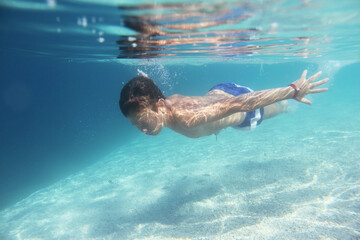 Fototapeta na wymiar Boy swimming underwater
