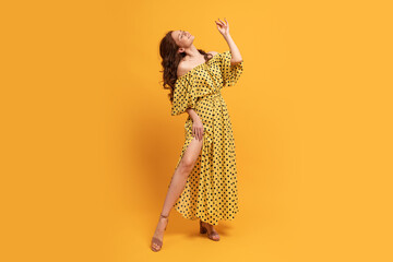 Red-head woman in yellow dress posing in studio. Summer mood. Full lenght.