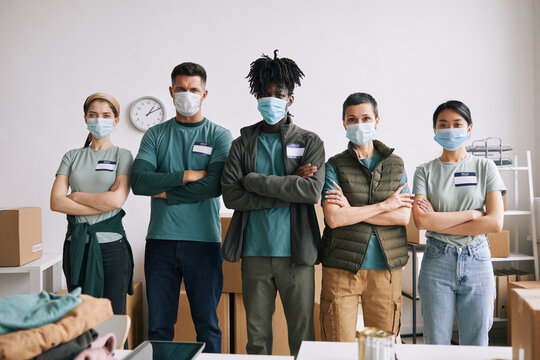 Diverse Team Of Volunteers Wearing Masks While Standing With Arms Crossed During Help And Donation Event, Copy Space