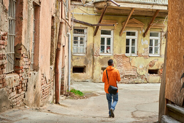 Fototapeta na wymiar A lonely guy walks in the old part of the city between dilapidated houses