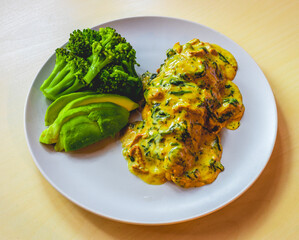 Chicken breasts in cream sauce with avocado and broccoli as a side dish