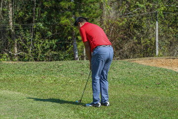 Fototapeta premium Golfer are playing game golf and hitting go on green grass mountain background. Asia male player game shot in summer. Sport holiday lifestyle concept.