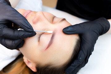the master of permanent makeup washes off the remaining pigment after the tattoo procedure with a...