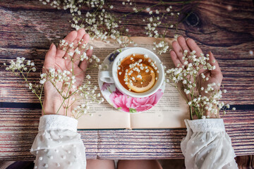 Cup of tea with lemon and opened book on the table in the room. 