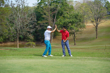 Obraz premium Shot of two golfers congratulating each other with a high five after a game of golf.