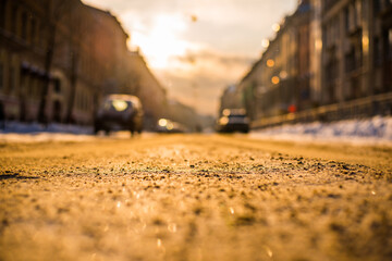 Bright winter sun in a big city, on the snowy street going cars. View from the road level