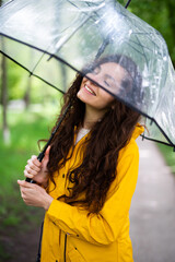 Hübsche Frau mit Regenjacke und Regenschirm draußen in der Natur