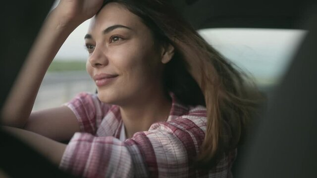Young woman looking out of the window's car while having a road trip