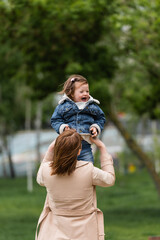 mother holding in arms excited autistic toddler child in park