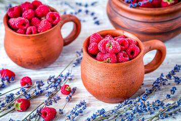 raspberry in pottery and lavender flowers on rustic background